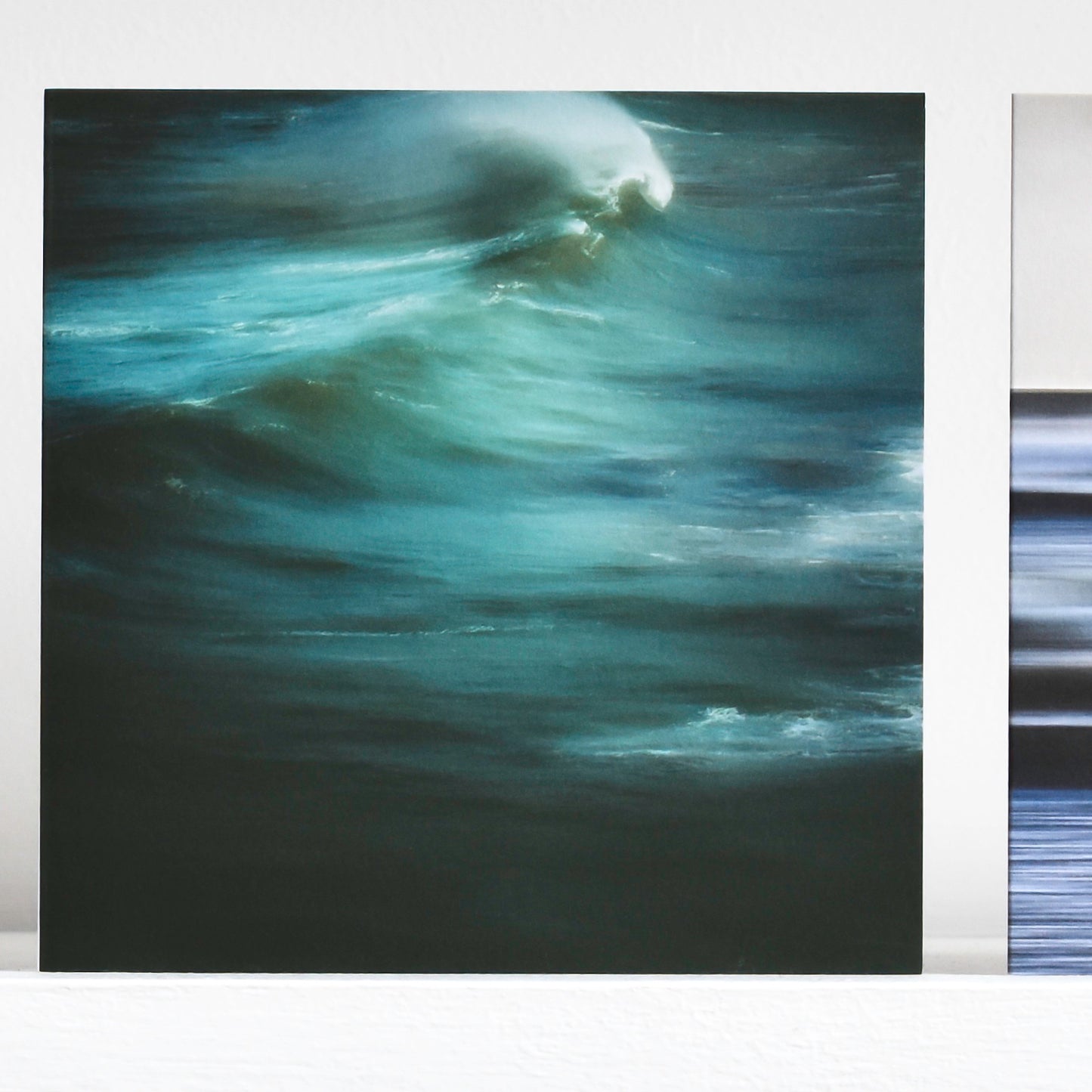 Art card showing green wave with white spray, moody and evocative