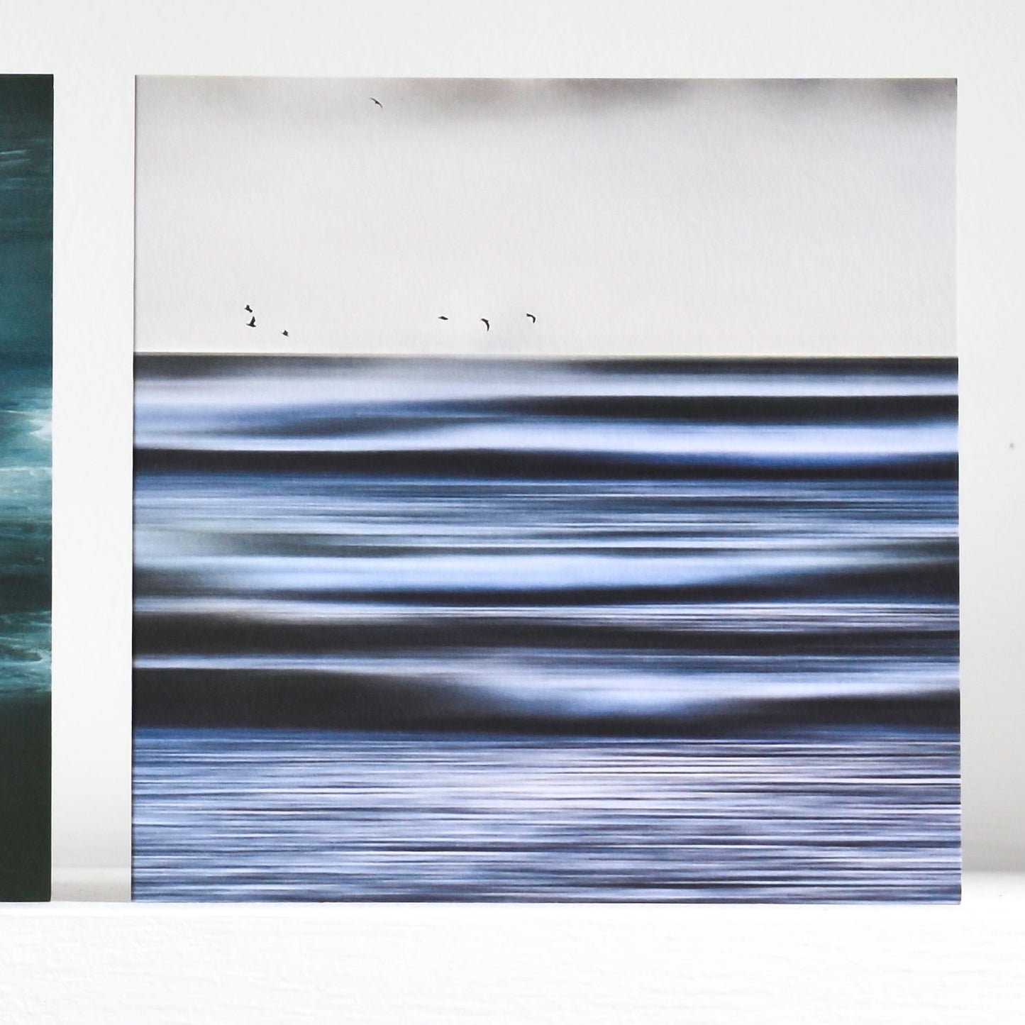 Abstract art card showing gulls flying over blurred lines of incoming waves