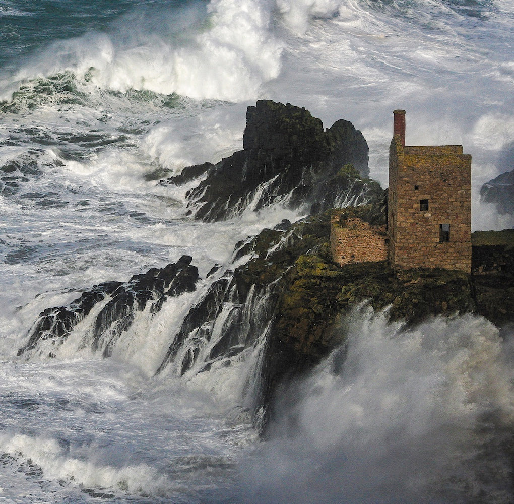 Cornish Engine House on rocks amid big waves, at Botallack, Cornwall