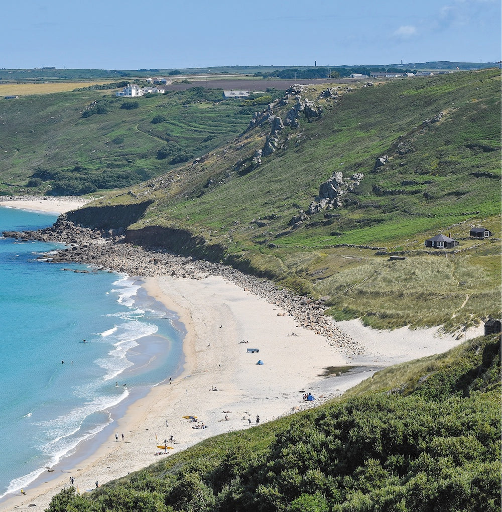 An Evocative Cornwall greetings card image looking down at the white sands and turquoise water of Sennen Beach and the surrounding granite crags of the cliffs, terraced hillside and dunes.