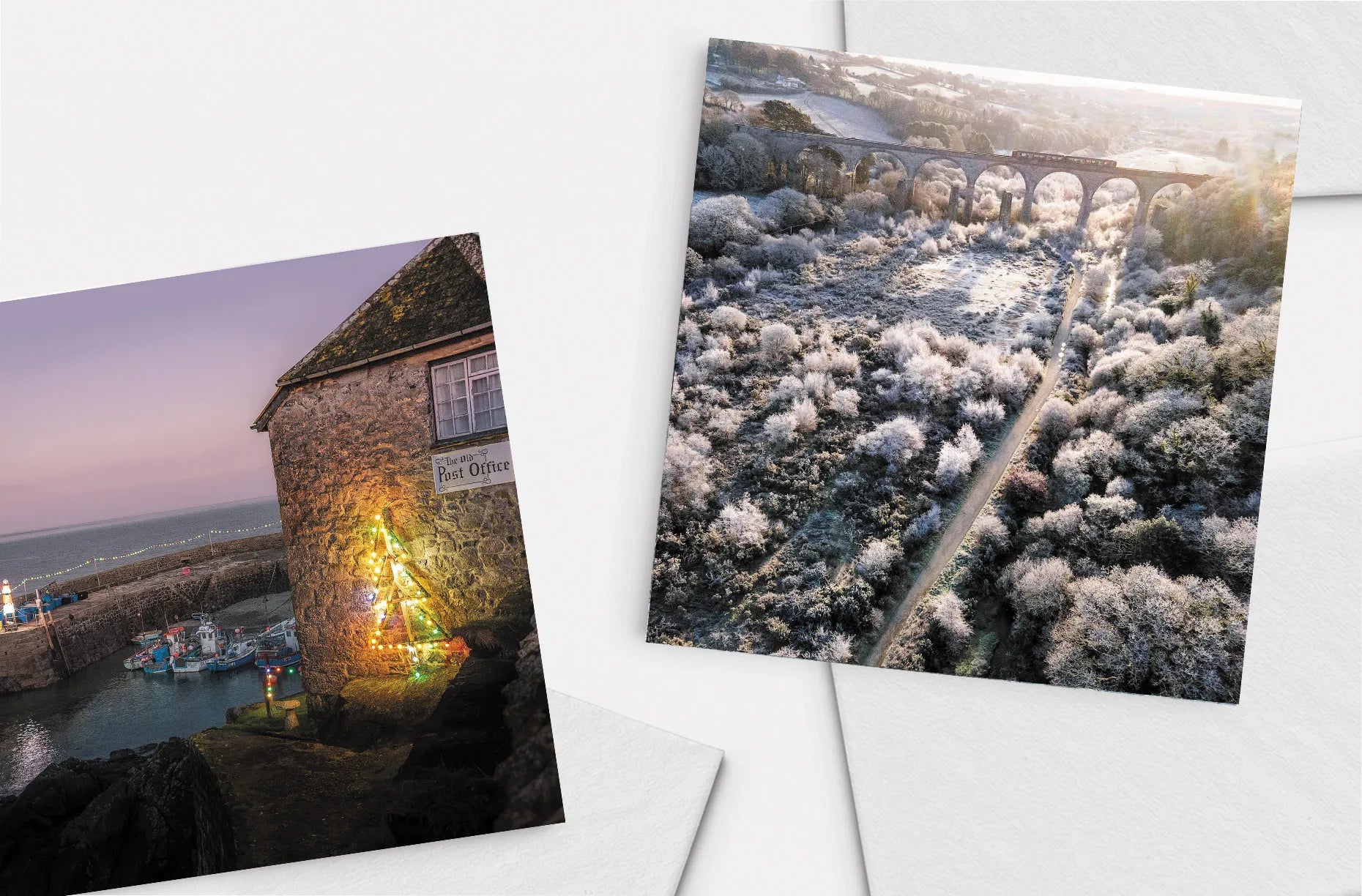 A selection of two Cornish Christmas cards, depicting a train passing over the Carnon Viaduct on a frosty morning, and the Christmas lights at Coverack Harbour