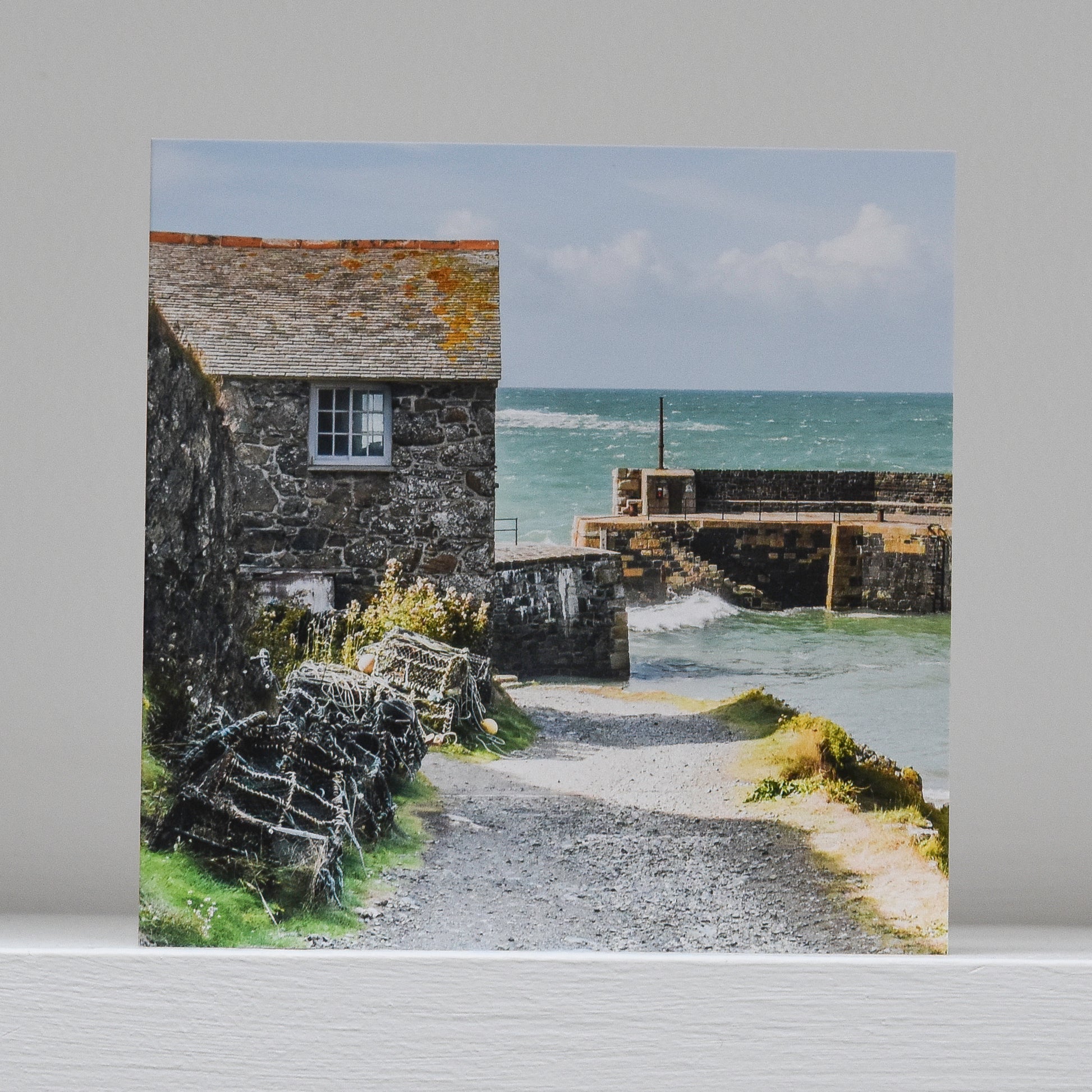 Greetings card on shelf showing image of the net loft and harbour walls at Mullion
