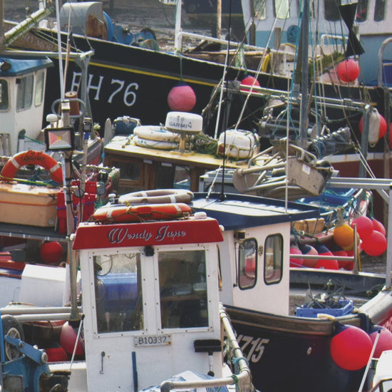 Video animation of greeting card image showing fishing boats in the harbour at Mevagissey, colourful  with buoys over their sides