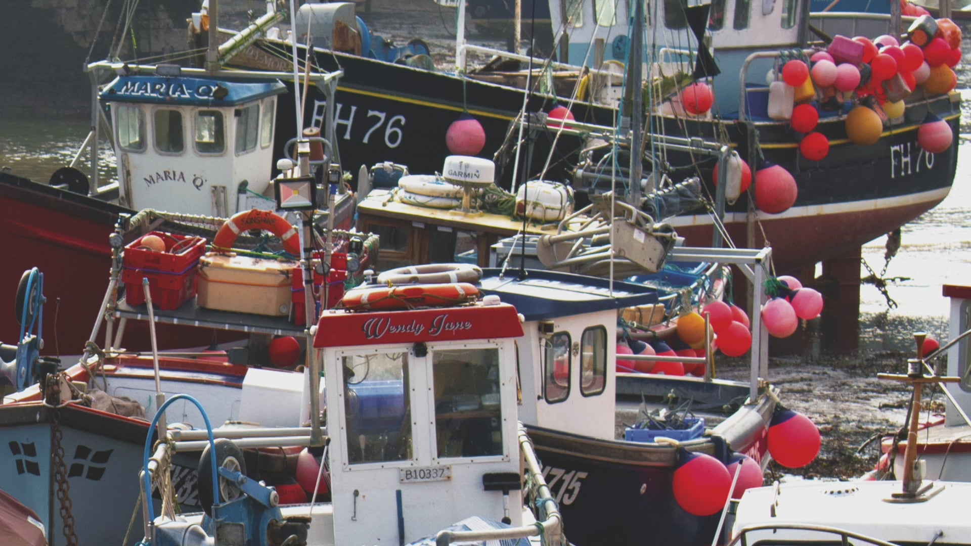 Video animation of greeting card image showing fishing boats in the harbour at Mevagissey, colourful  with buoys over their sides