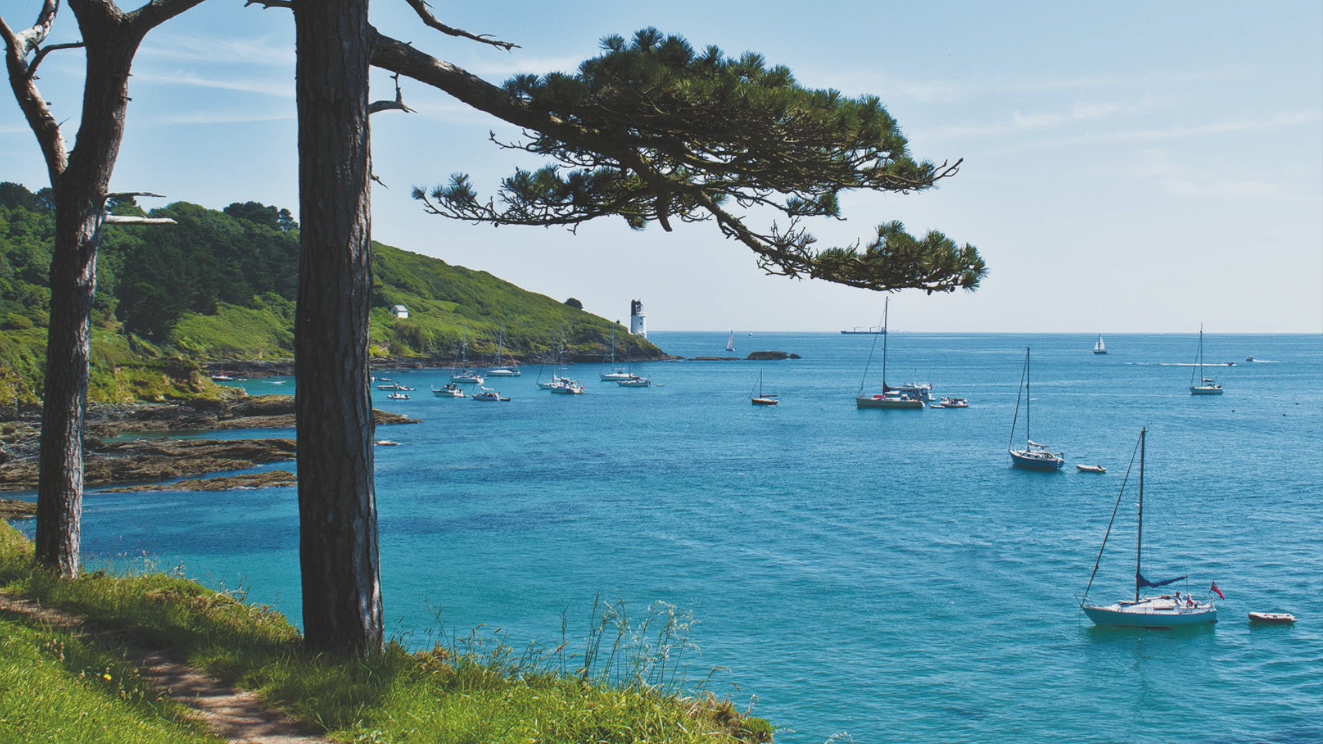 Video animation of a greeting card showing the lighthouse at St Antohony Head, with yachts at anchor in a bay of aquamarine water, with the coast path snaking between pines