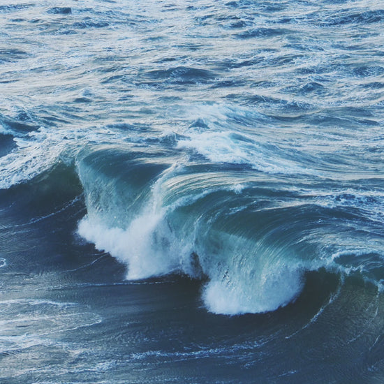 Video animation of a greeting card showing a wave breaking at the entrance to Port Isaac harbour, all in blues