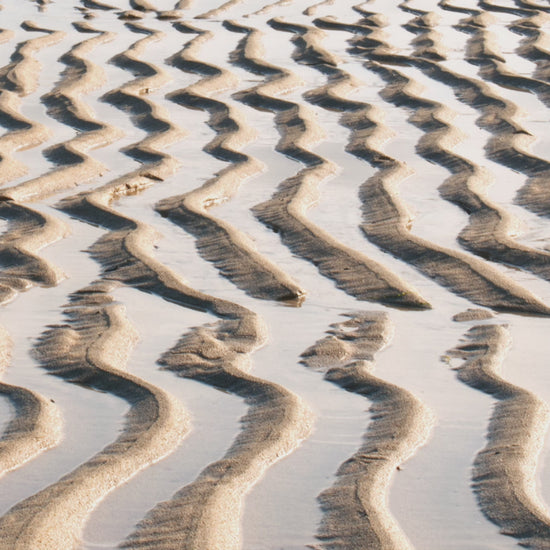 Video animation of greetings card showing ripples in the sand at Hayle beach, with dark cliffs in the background.  Moody, Scandinavian tones